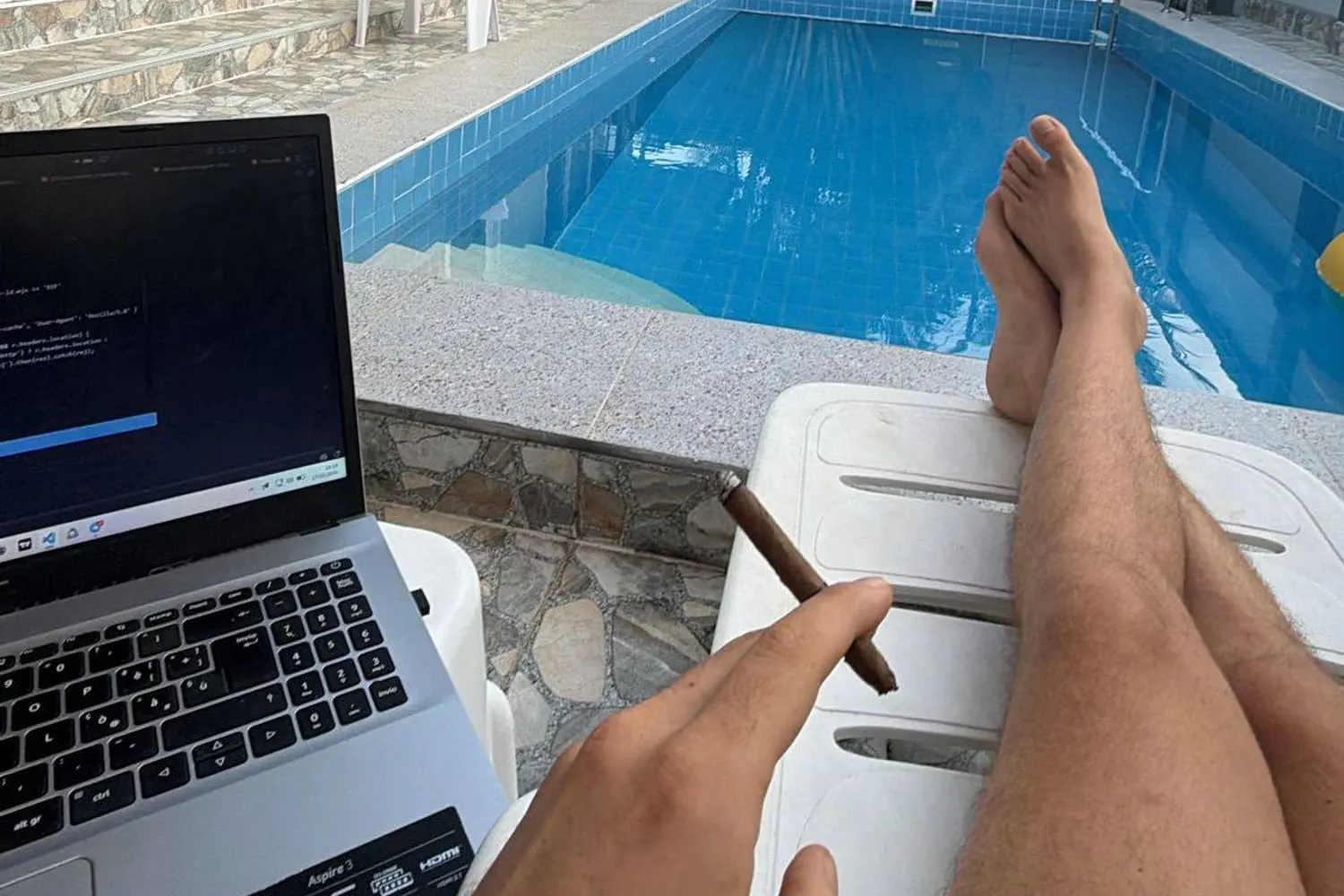 A laptop showing code on a poolside lounger with a cigar, a solopreneur one person setup.