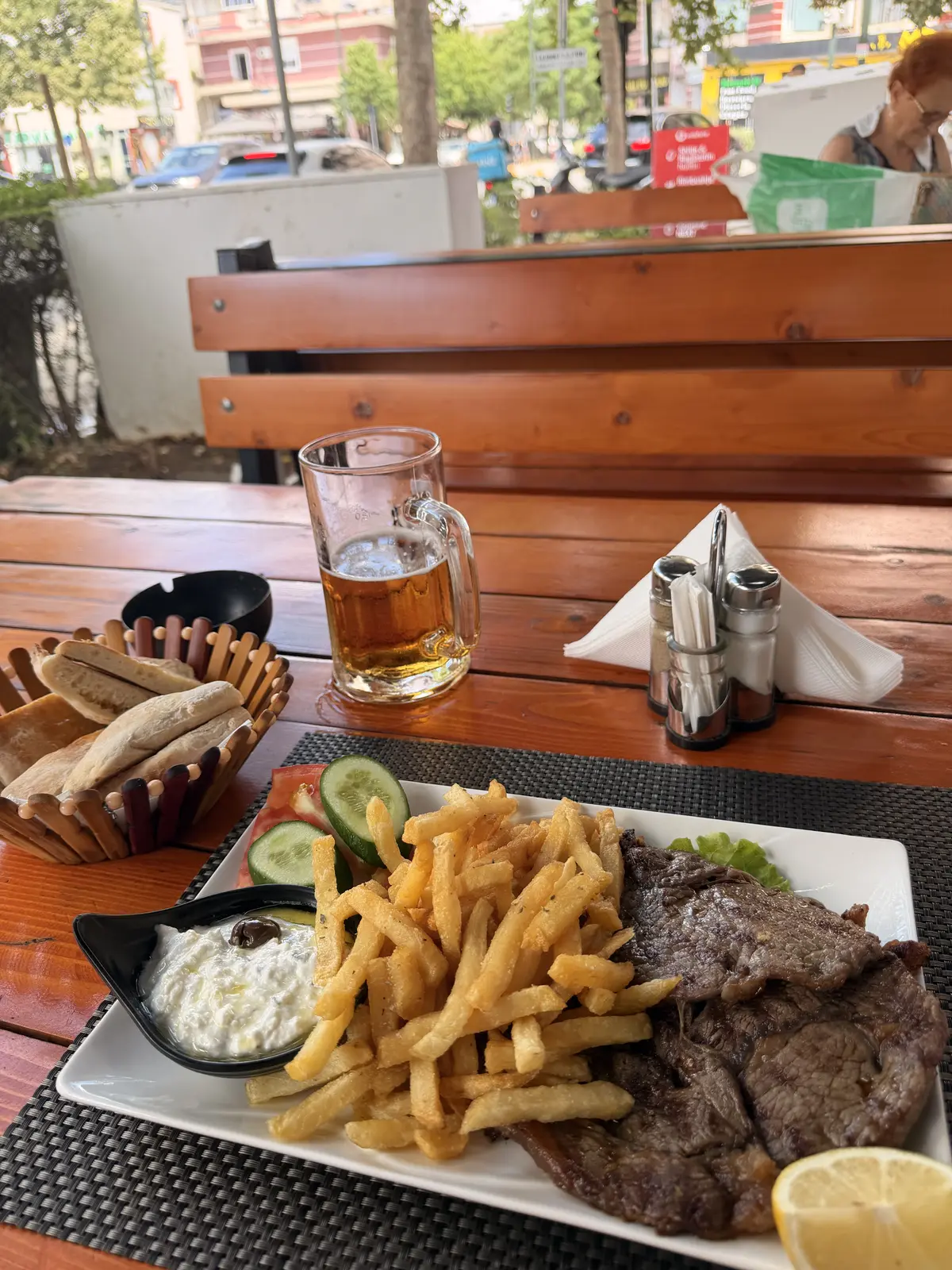 Una terrazza tranquilla di un ristorante con una birra e un piatto, affacciata sulla costa albanese.