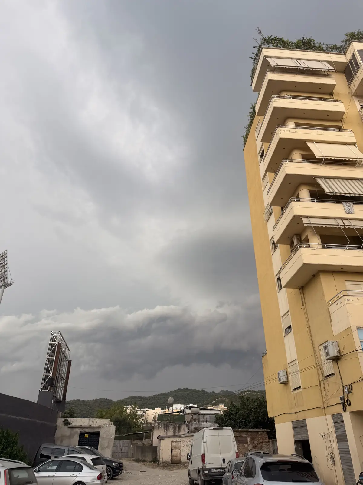 Nuvole scure da temporale si addensano dietro un palazzo di appartamenti in cemento non finito a Valona.
