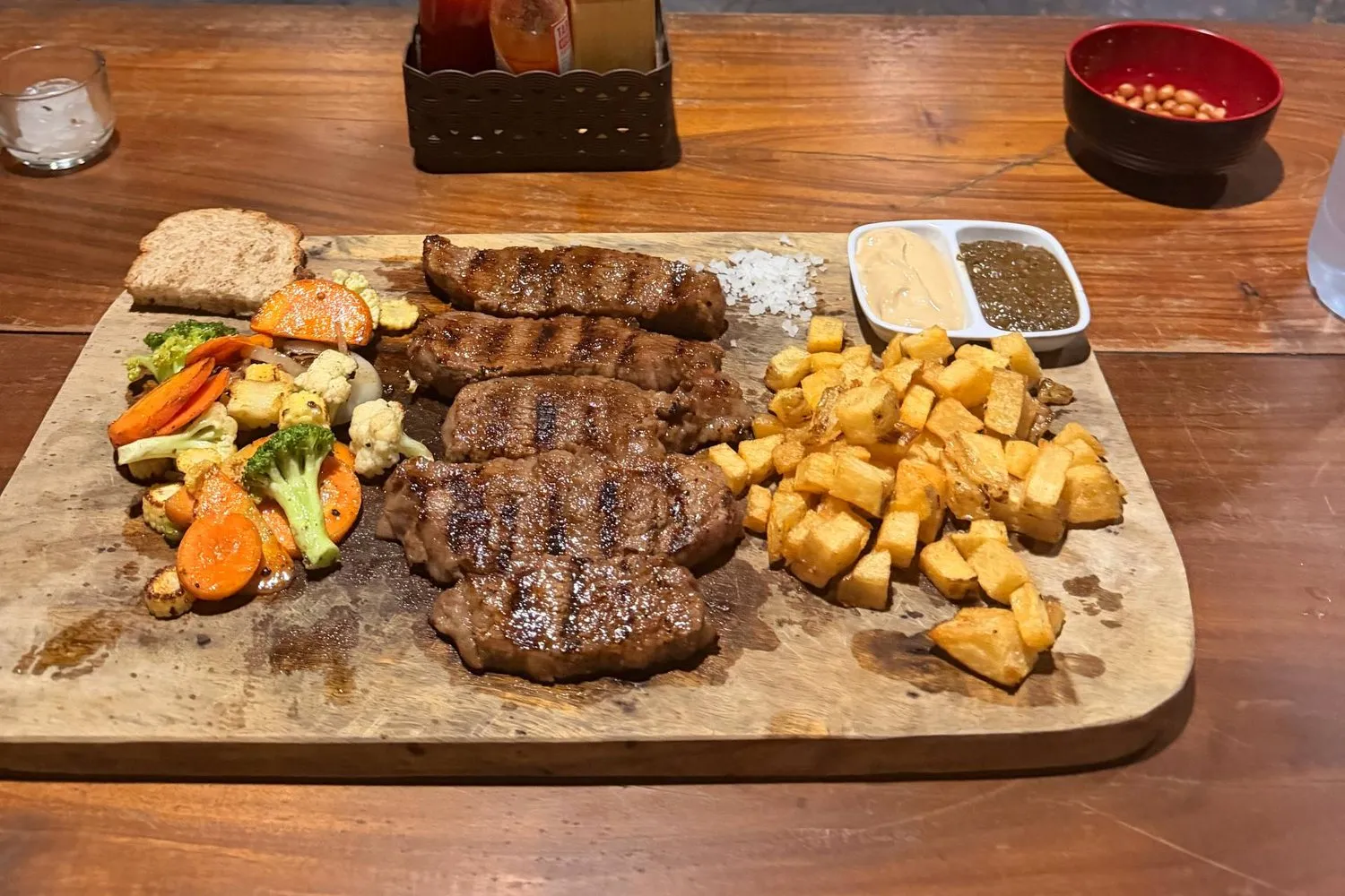 Un tagliere di carne alla griglia con patatine e verdure in un ristorante con griglia aperta a Canggu, Bali.