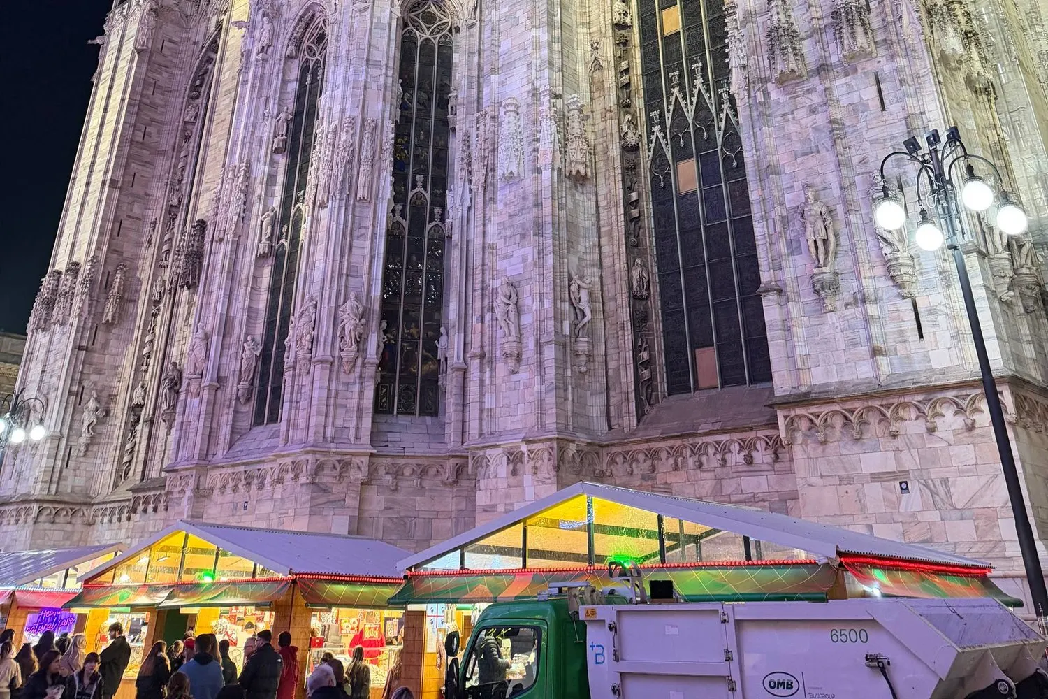 The Duomo lit at night above a Christmas market in Milan, Italy.