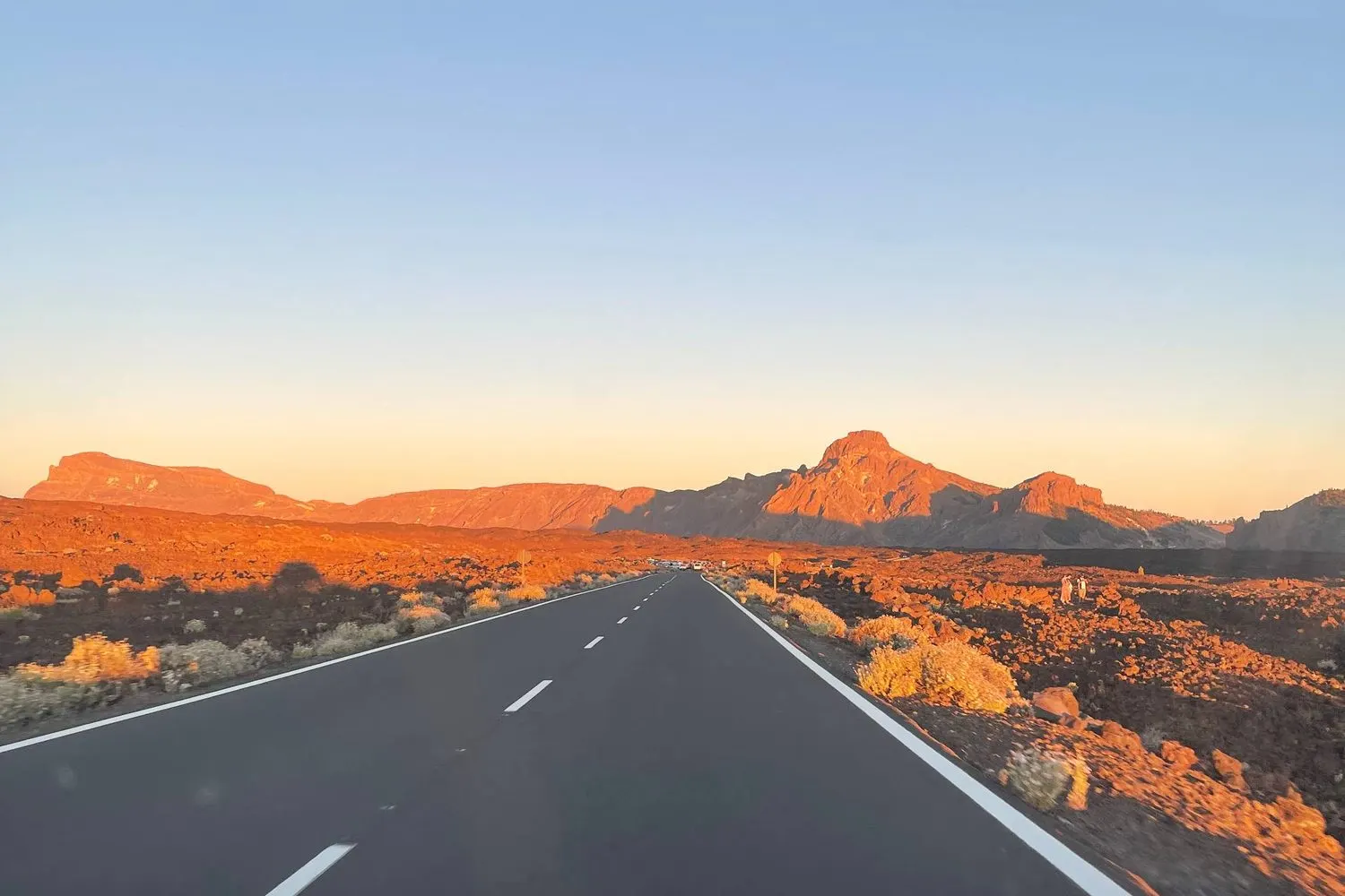 Una strada vuota verso le cime vulcaniche rosse del Teide al tramonto, Tenerife.