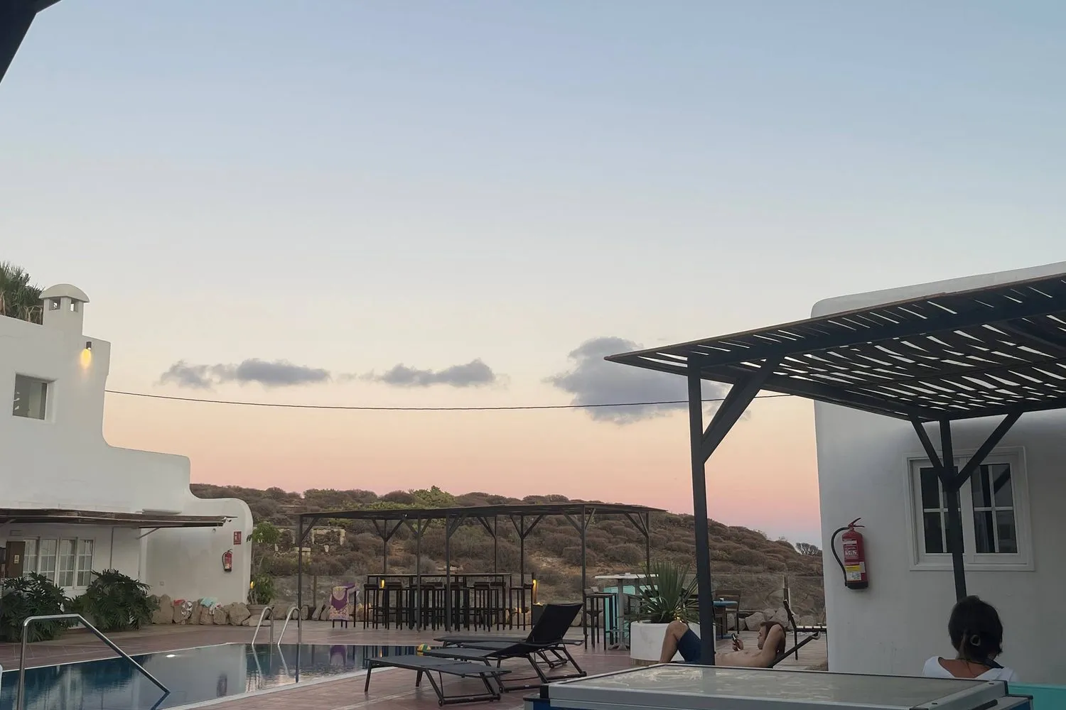 Una villa bianca con piscina, sgabelli da bar e un pergolato al tramonto nel sud di Tenerife.